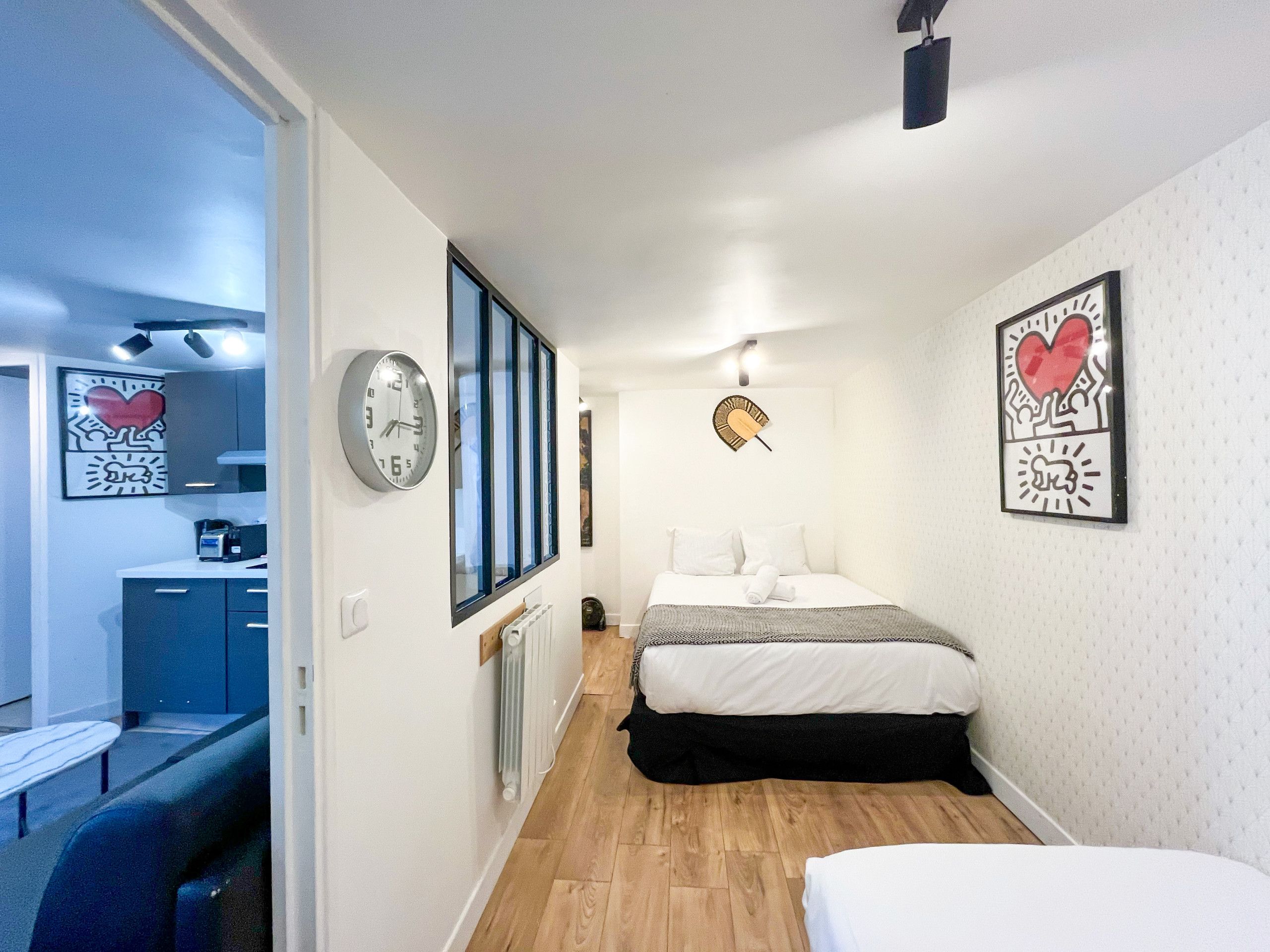 Un dormitorio moderno con cama, mesita de noche, radiador y ventana con persianas.