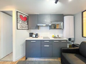 A compact kitchen with grey cabinets, a built-in microwave, and a coffee maker. - Urban Flat 150 - Pretty Flat in Center of Paris (París)