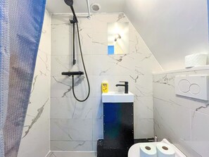 Un baño con ducha, lavamanos e inodoro.