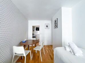 A room with a dining table, chairs, a bed, and a kitchen in the background. - 142 - Urban Pretty Flat in Montorgueil (París)
