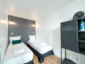 Ein Hotelzimmer mit zwei Einzelbetten, einem Kleiderschrank und einem Wandventilator.