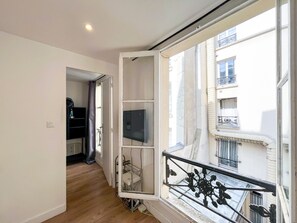 Ein Zimmer mit einem großen Fenster, einem Fernseher und einem Holzboden.