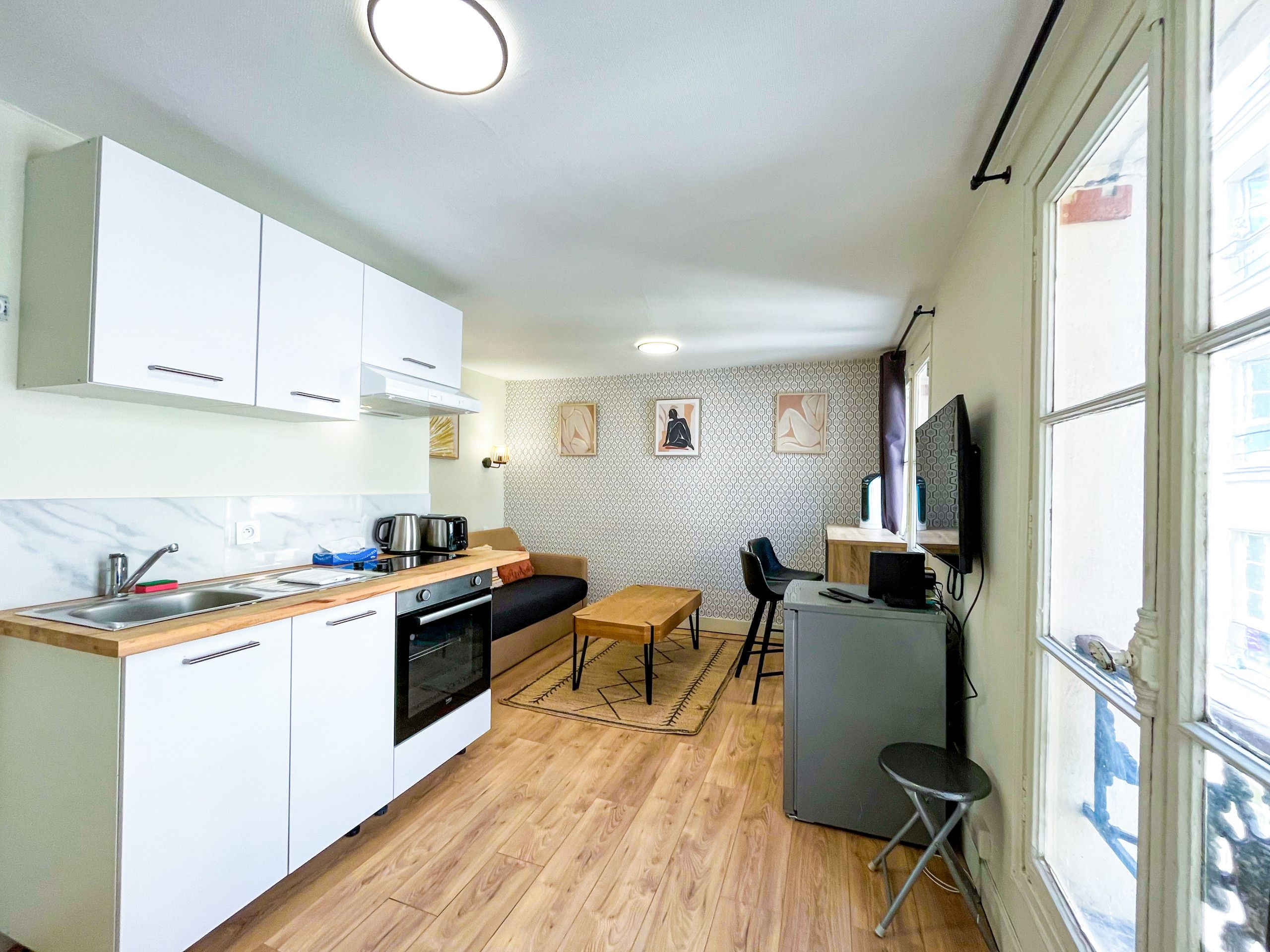 A compact kitchen with a dining area, a small refrigerator, and a television.