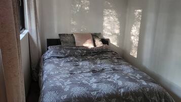 A bedroom with a bed, a window, and curtains.