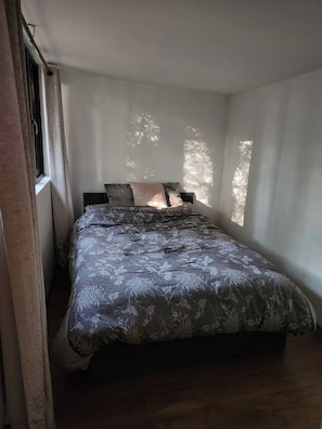 A bedroom with a bed, a window, and curtains. - Badgers Den at The Secret Garden (Ashford)