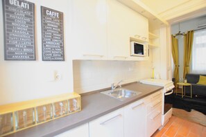 A modern kitchen with white cabinets, a stainless steel sink, and a microwave. - Hi5 Apartments - Chainbridge (Budapest)