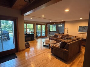 A spacious living room with a leather sofa, a round coffee table, and a wooden floor. - Waterfront house on Lake Wallenpaupack w/ private dock, sleeps 9, dogs allowed! (Tafton)