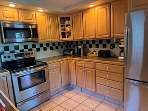 A kitchen with wooden cabinets, stainless steel appliances, and a checkered backsplash. - Waterfront house on Lake Wallenpaupack w/ private dock, sleeps 9, dogs allowed! (Tafton)