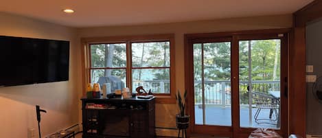 Una sala de estar con un sofá de cuero, un televisor montado en la pared, una mesa de centro de madera y un ventanal con vistas al exterior.