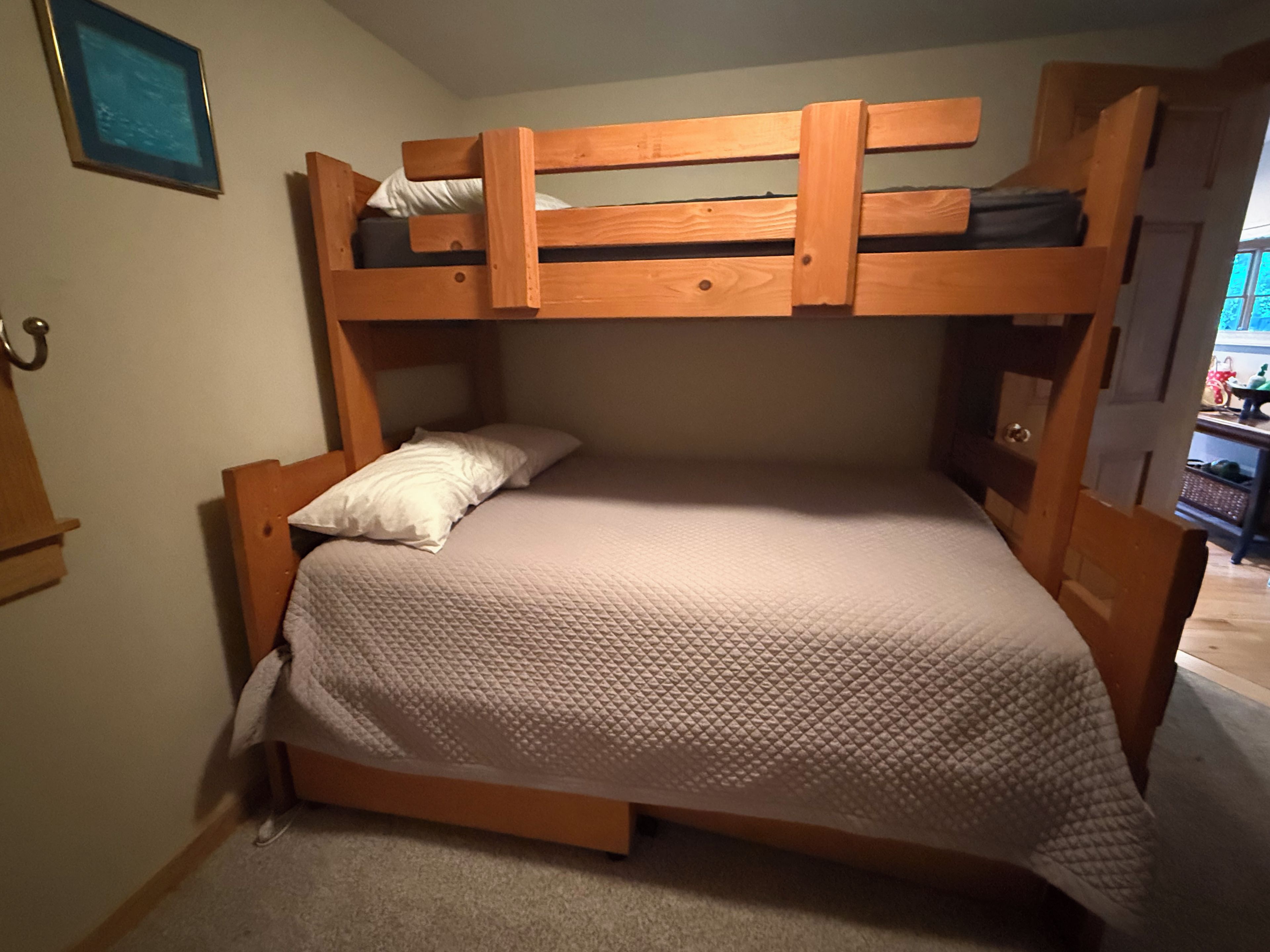 A bunk bed with a wooden frame, a single pillow, and a quilted mattress.