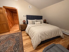 Une chambre à coucher avec un lit, des tables de chevet, un tapis et une porte en bois.