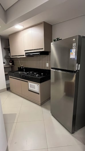 A modern kitchen with a stainless steel refrigerator, a built-in oven, and a gas stove. - FLAT NA MELHOR LOCALIZAÇÃO DA ORLA (Palmas)