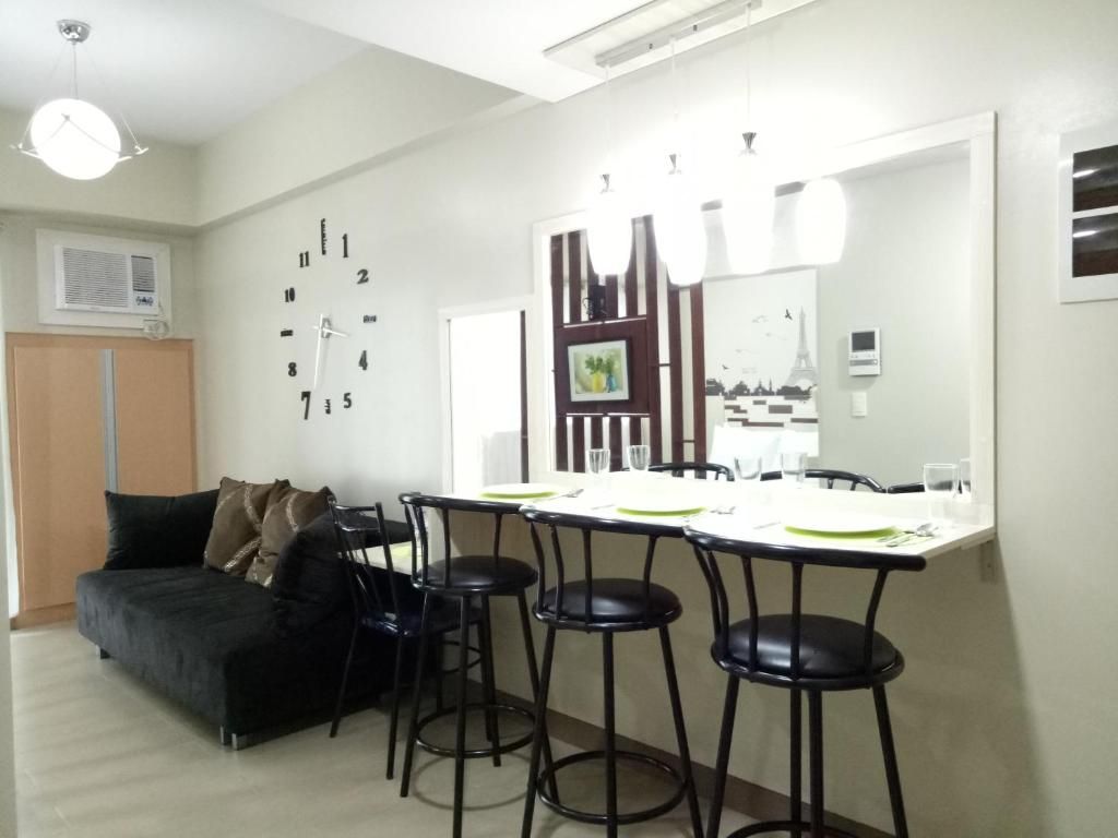 A modern living room with a sofa, a dining table with chairs, and a large mirror.