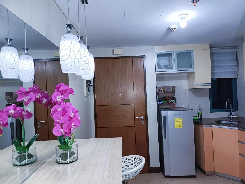 A modern kitchen with a refrigerator, cabinets, and a dining area with a table and chairs.