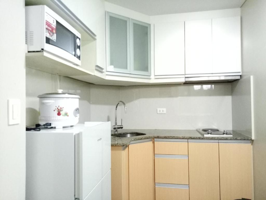 A kitchen with white cabinets, a microwave, a stove, and a sink.