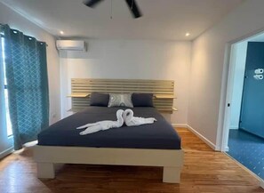A modern hotel room with a large bed, a headboard with horizontal slats, and a pair of towels arranged on the bed. - Casa Cerro Verde in Ojochal (Osa)