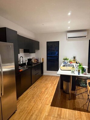 A modern kitchen with a stainless steel refrigerator, black cabinets, and a wooden floor. - Casa Cerro Verde in Ojochal (Osa)