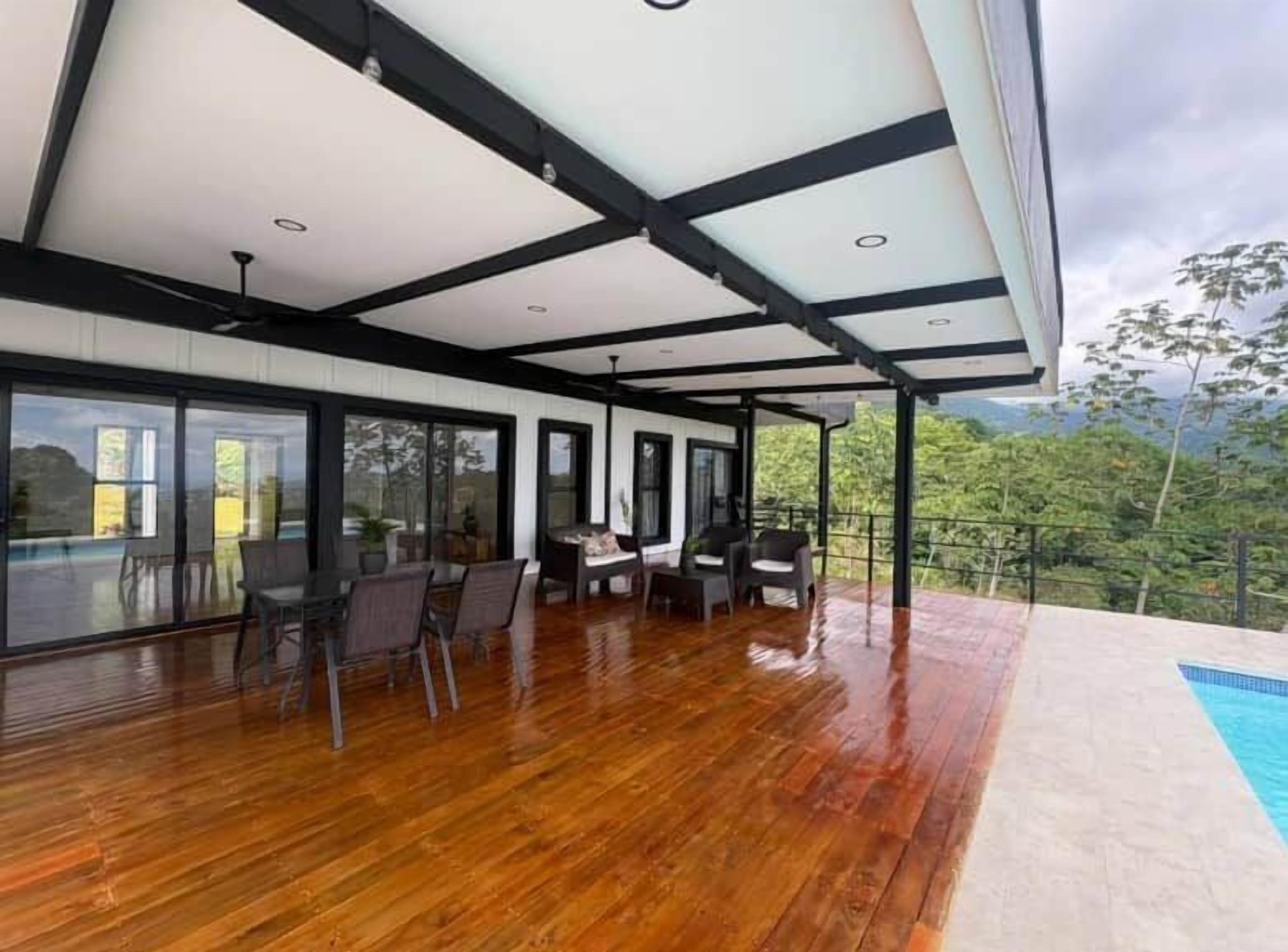 Un espace extérieur abrité, doté d’un plancher en bois, d’une piscine et offrant une vue sur le paysage environnant.