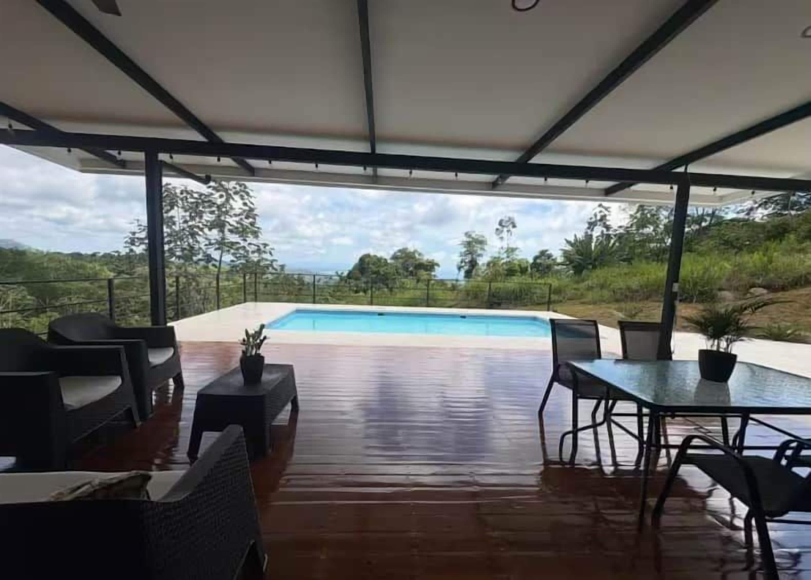 An outdoor patio with a pool, seating, and a view of the landscape.