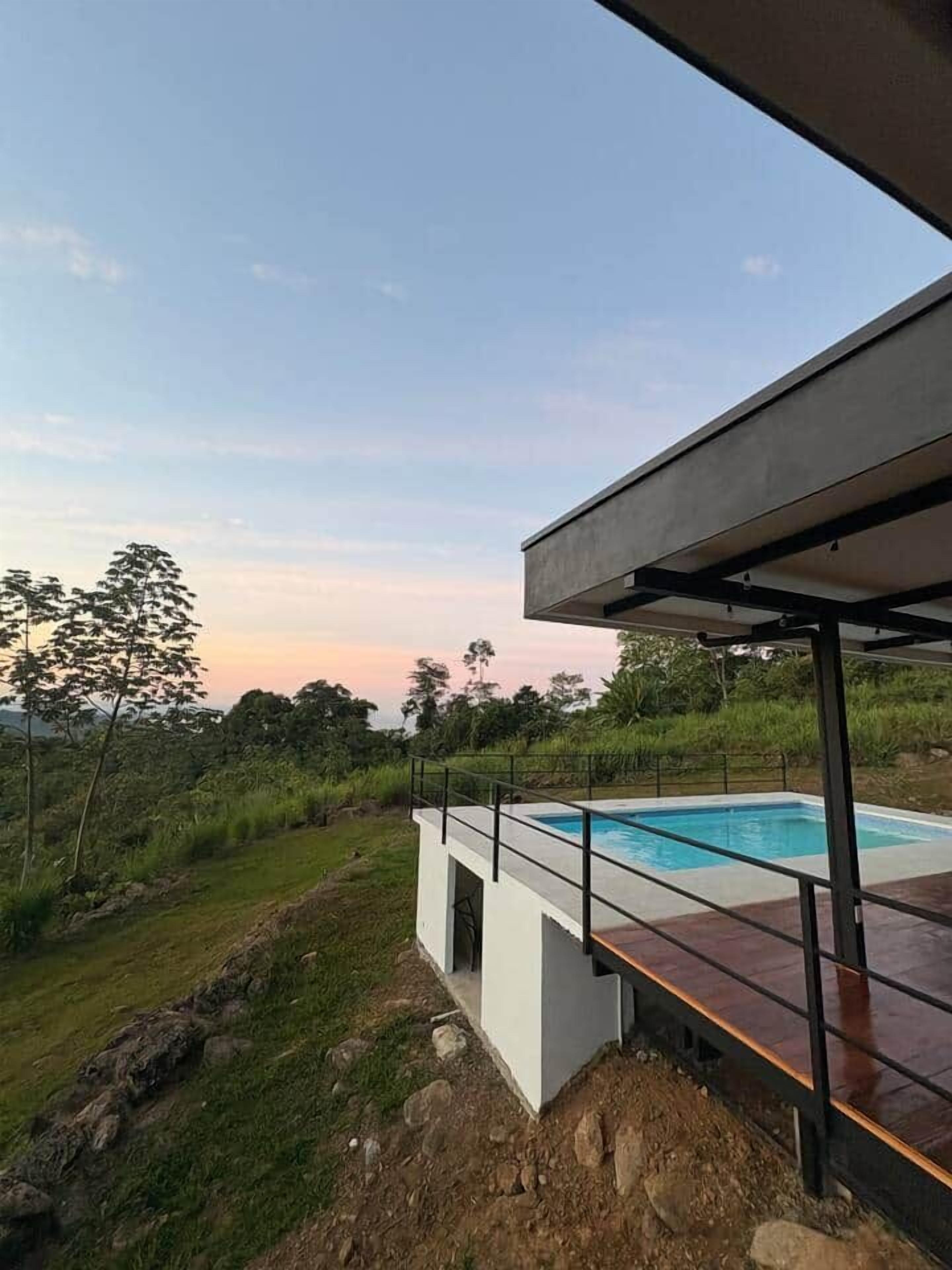 A modern outdoor pool area with a clear view of the sky and surrounding greenery.