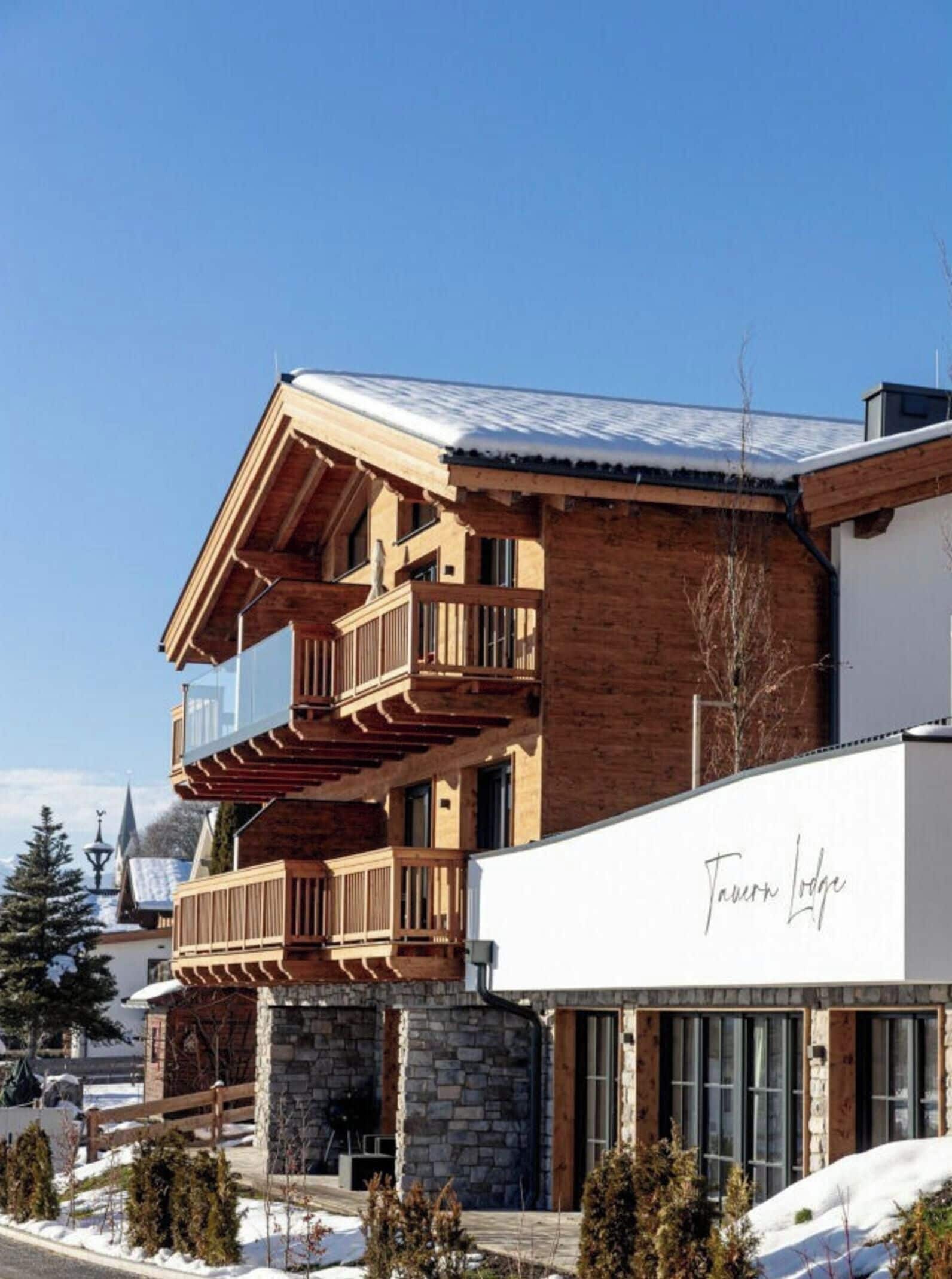 A multi-story building with wooden balconies and a stone base, named 'Tauron Lodge'.