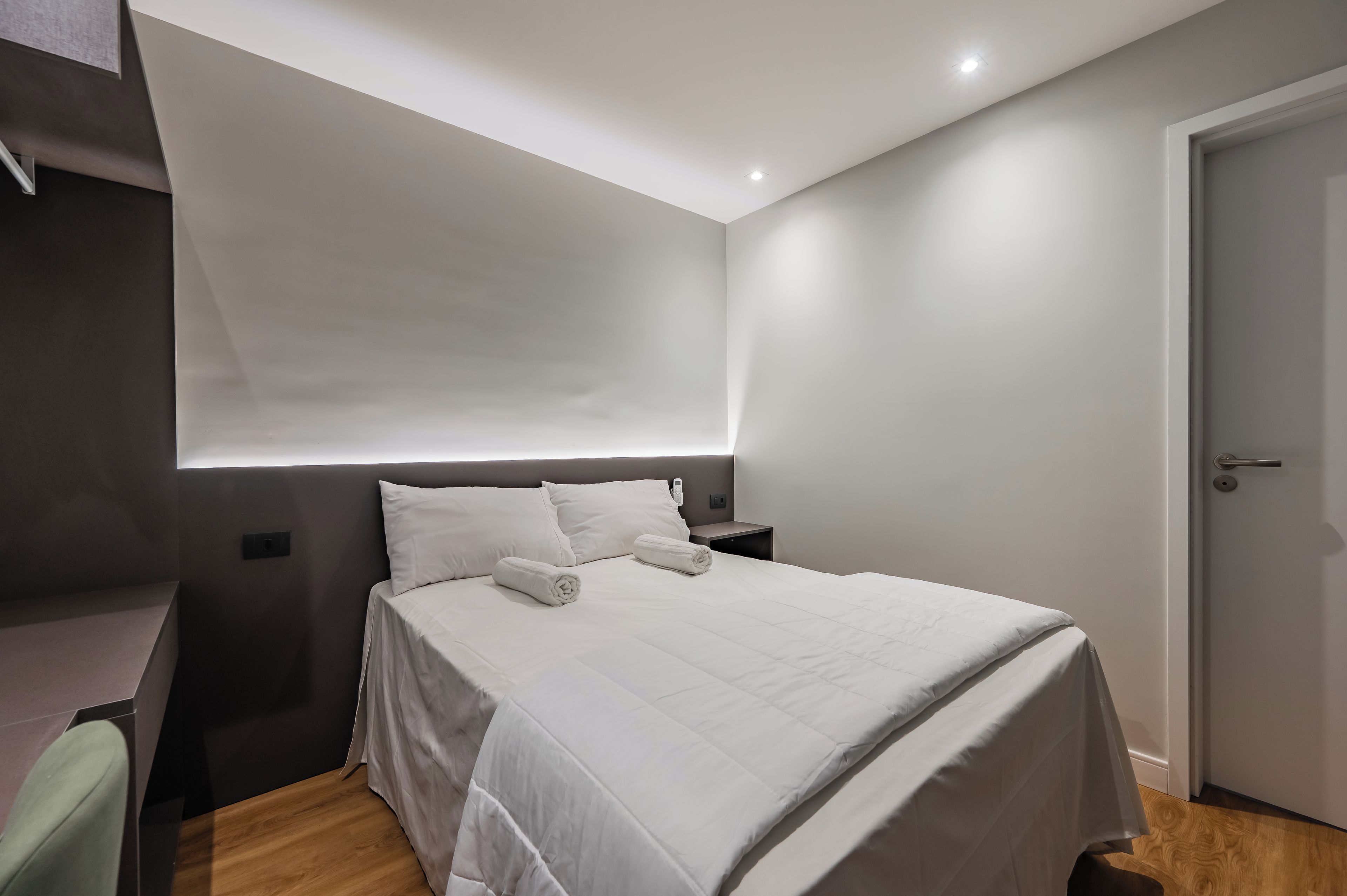 A modern bedroom with a bed, bedside tables, and a door.