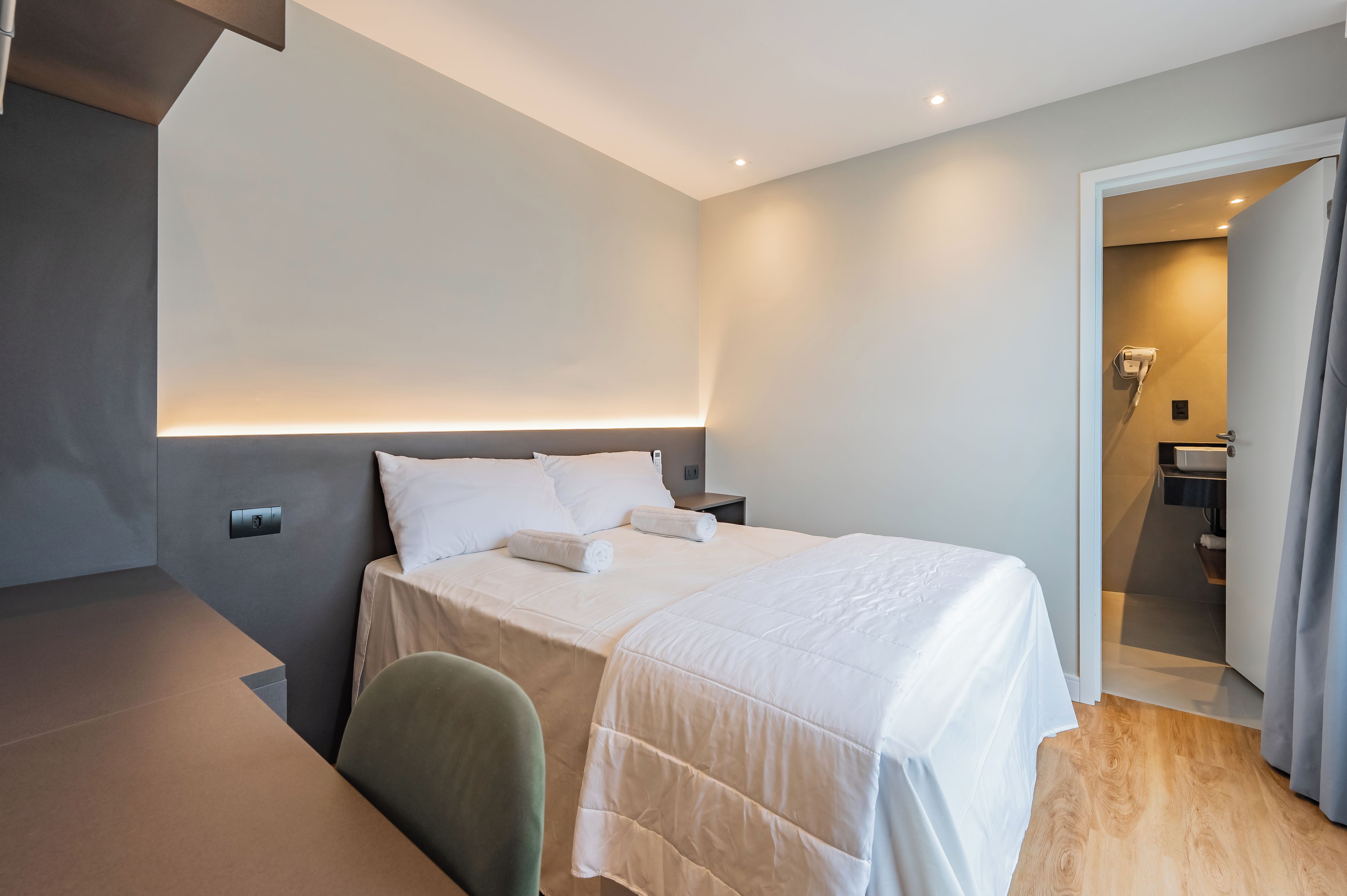 Una habitación de hotel moderna con una cama bien hecha, un escritorio y una silla.