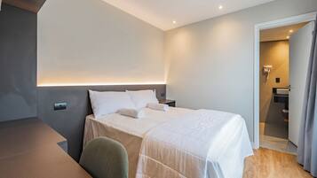Una habitación de hotel moderna con una cama bien hecha, un escritorio y una silla.