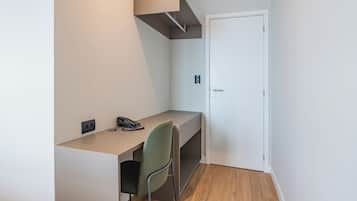 Et lille, funktionelt værelse med skrivebord, stol og dør.