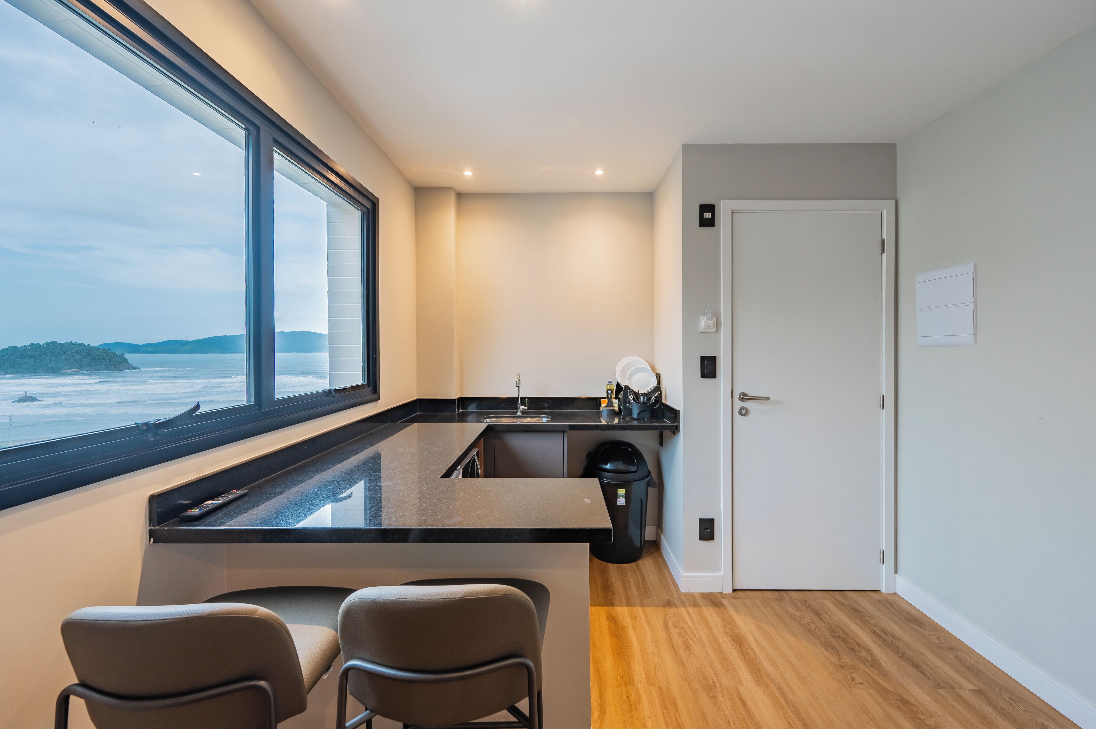 A modern kitchen with a large window, a sink, and two chairs.