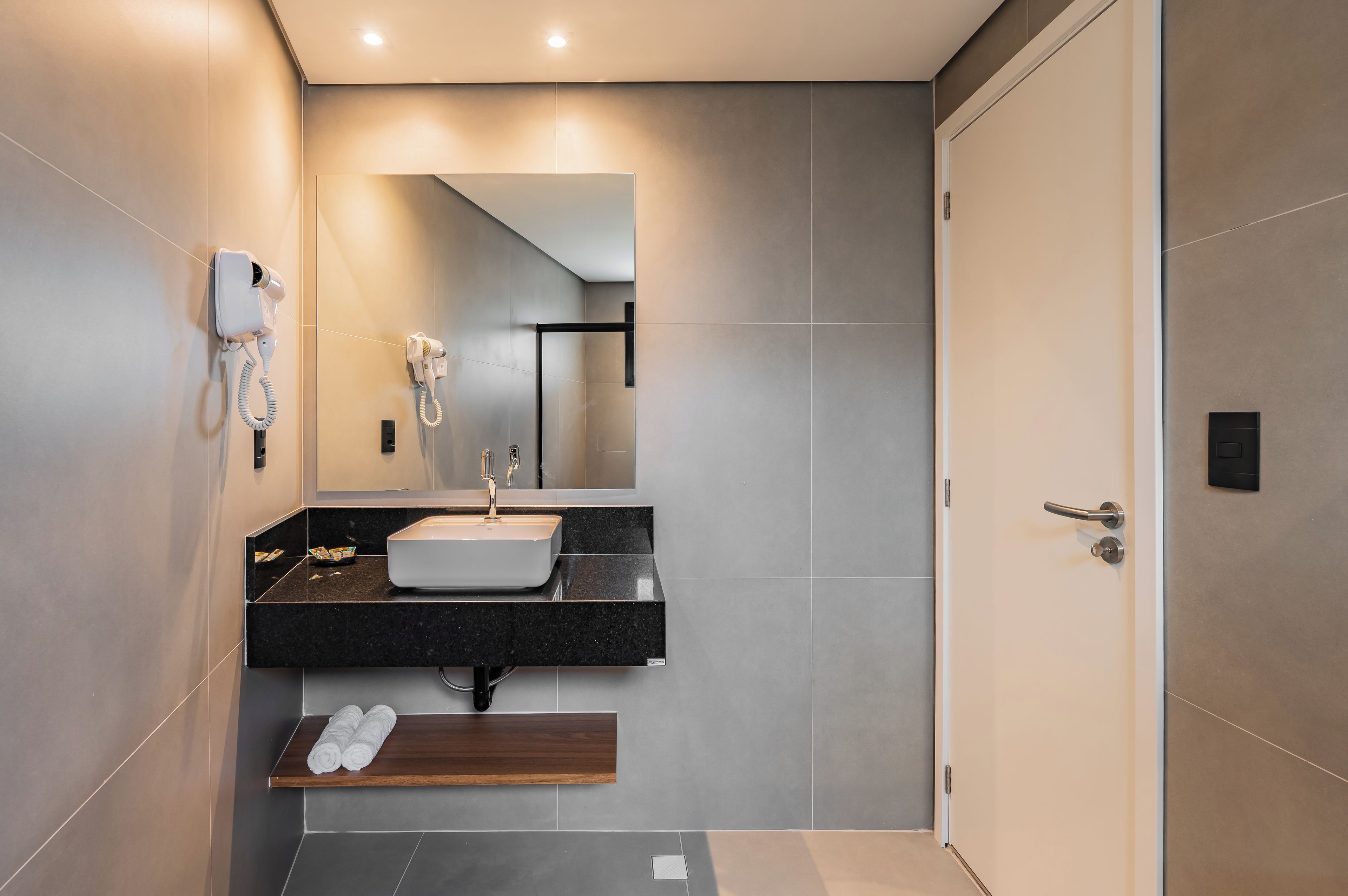 Un baño moderno con lavamanos integrado, un secador de pelo y un perchero para toallas.