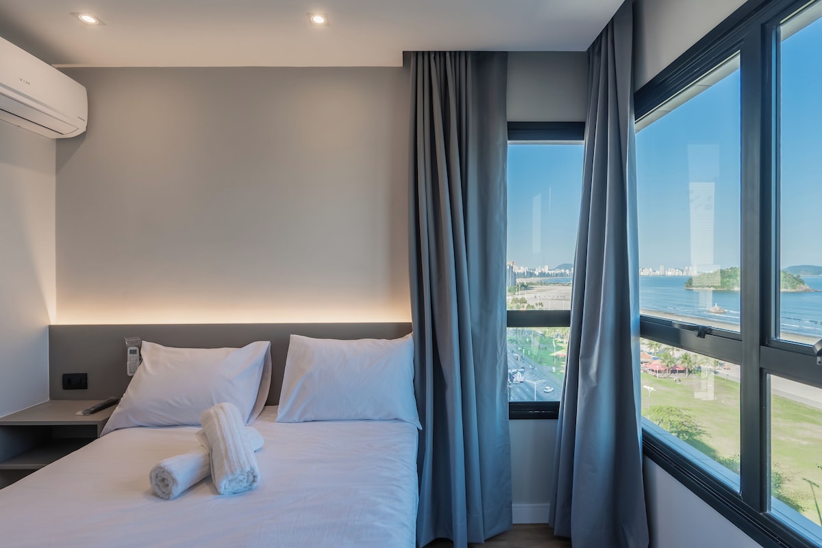 Ein modernes Hotelzimmer mit Bett, Nachttisch, Telefon und einem Vorhangfenster.