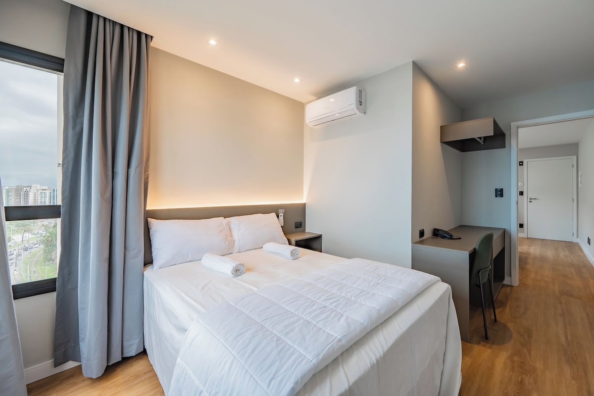 Ein Hotelzimmer mit Bett, Schreibtisch und Blick auf die Stadt.