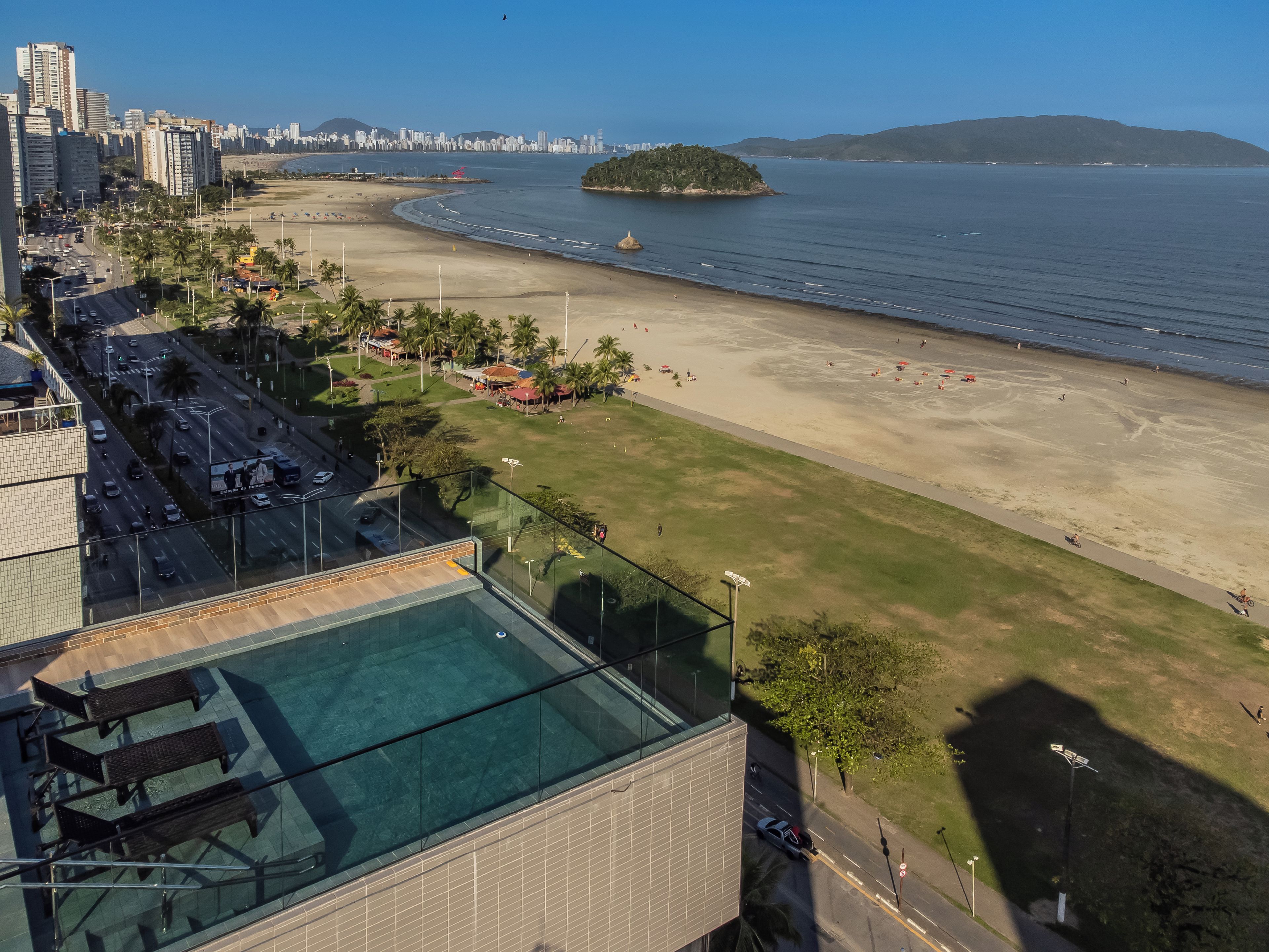 Ein Hochhotel mit Schwimmbad, Strand und Stadtblick im Hintergrund.