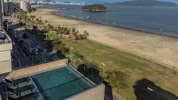 Ein Hochhotel mit Schwimmbad, Strand und Stadtblick im Hintergrund.