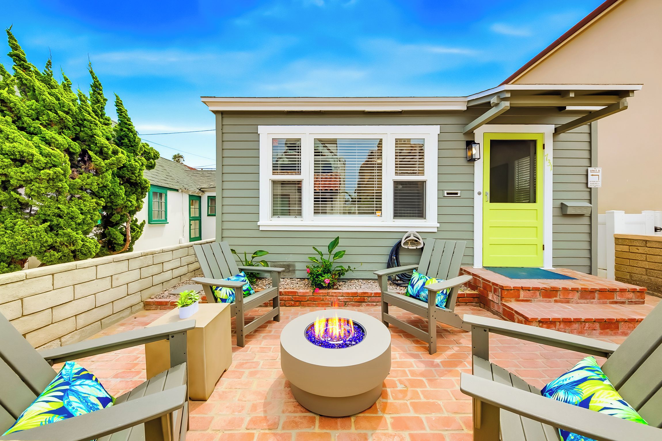 A patio with outdoor seating, a fire pit, and a house with a green door.