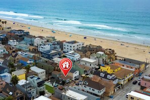 Zona residencial à beira-mar, com praia, casas e um marcador vermelho indicando a localização.