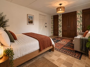 Een slaapkamer met een bed, nachtkastje, lamp en een groot raam.
