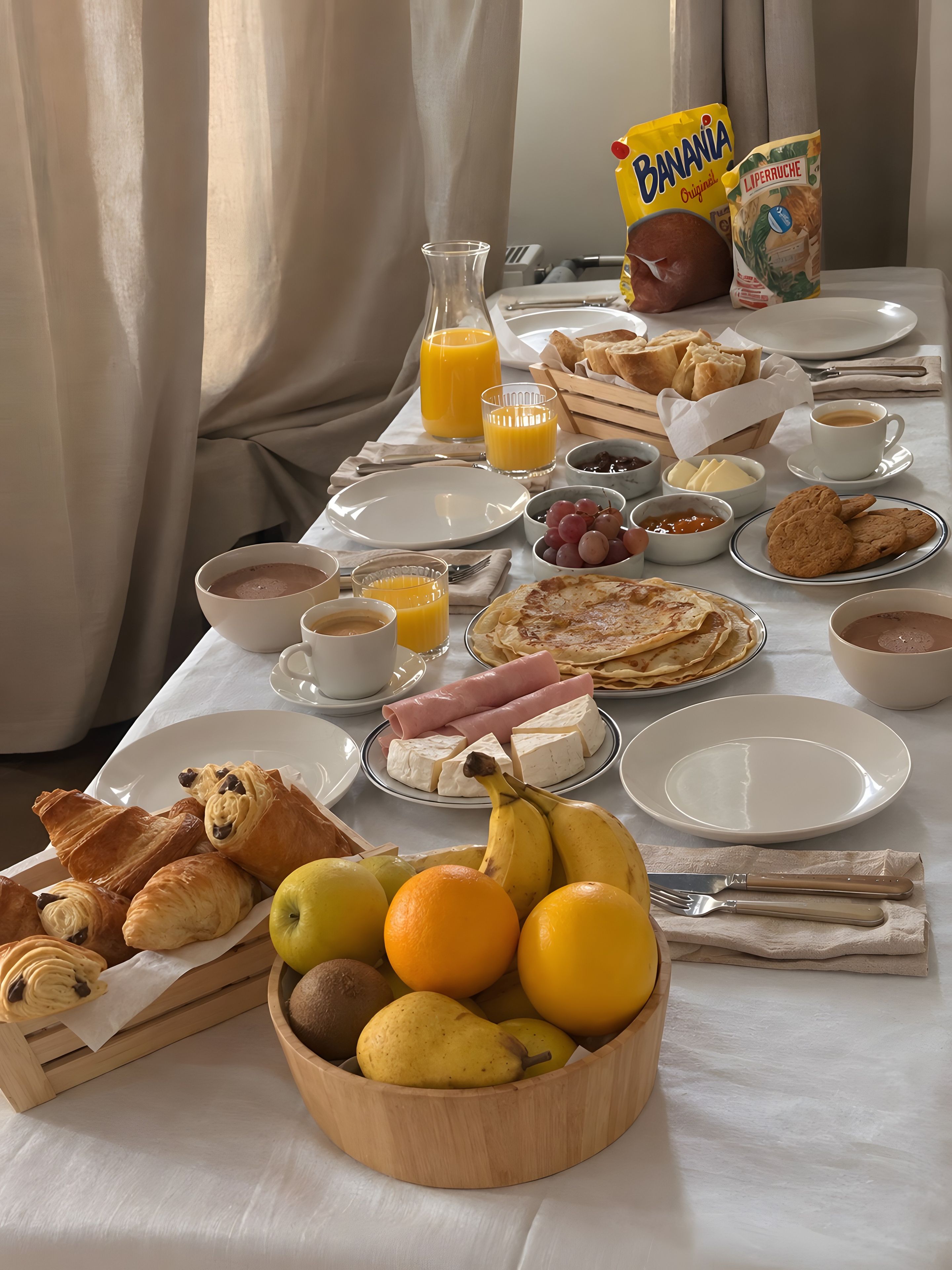 A breakfast table with various food items, including pastries, fruits, and beverages.