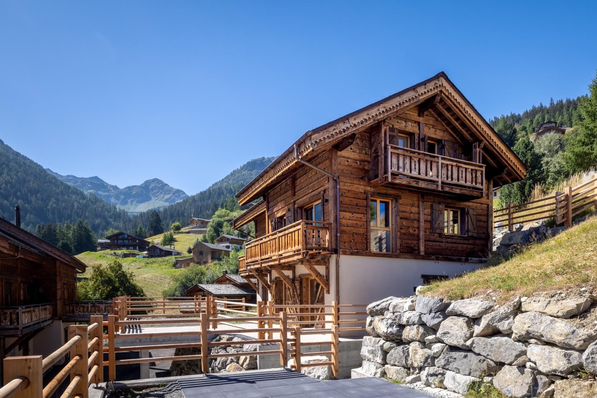 Eine Holzhütte mit Balkon vor einer Bergkulisse.