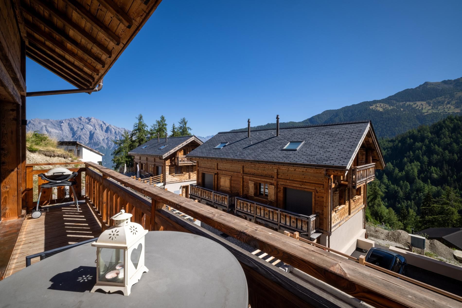 A wooden chalet with a balcony overlooking a mountainous landscape.