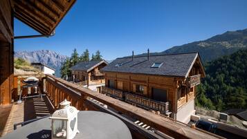 A wooden chalet with a balcony overlooking a mountainous landscape.