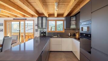 A modern kitchen with a central island, built-in appliances, and a view of the outdoors.