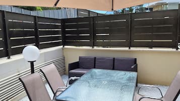Un espace extérieur aménagé avec une table et des chaises, un grand parasol et une clôture noire.
