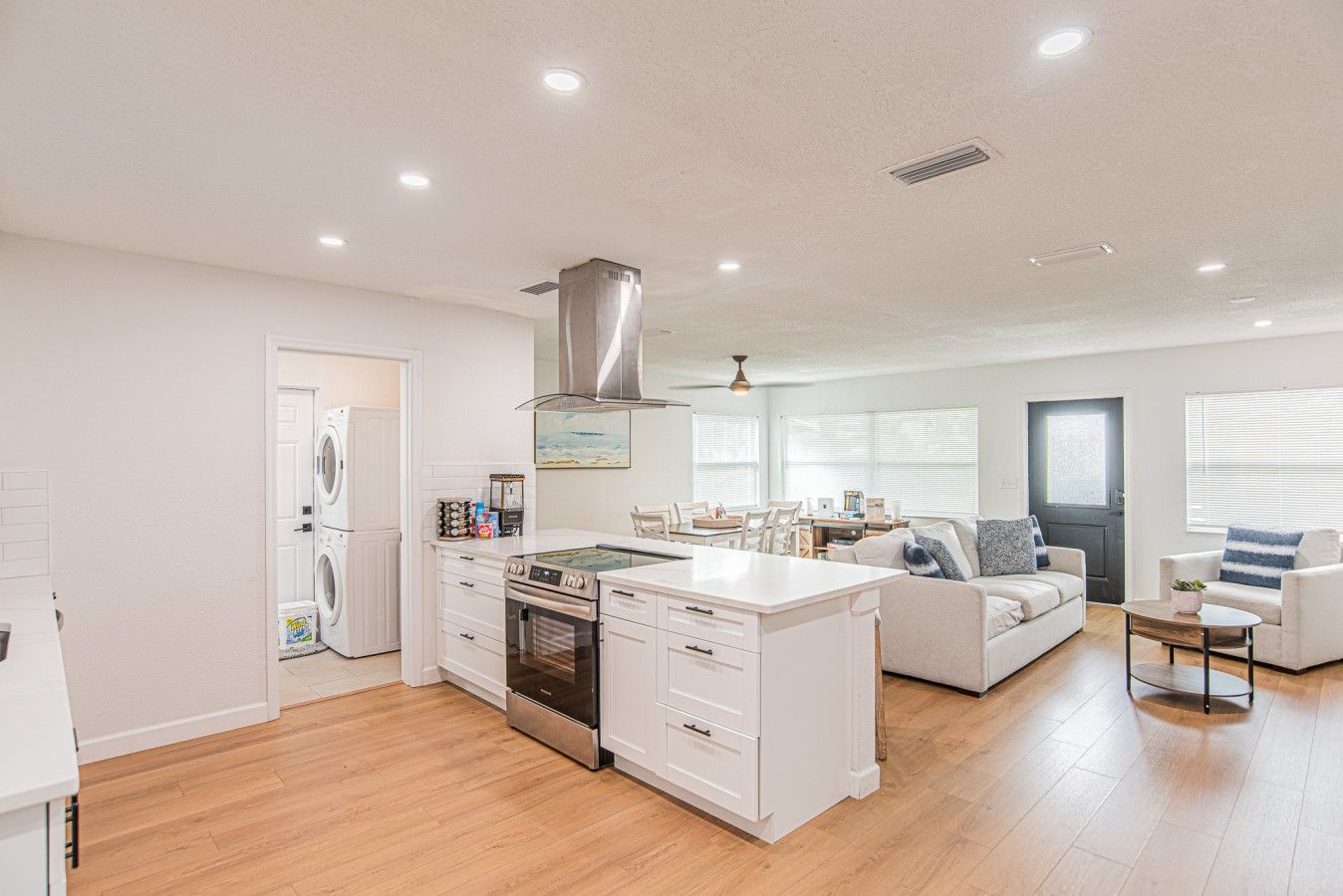 A modern kitchen with a central island, built-in oven, and stainless steel range hood.