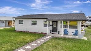 A single-story house with a front porch, a small garden, and two blue Adirondack chairs. - Hernando Beach Breeze | Waterfront Hot Tub, Kayaks (Hernando Beach)