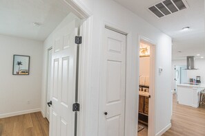 A hallway with white doors, a kitchen area with a stove and cabinets, and a framed picture on the wall. - Hernando Beach Breeze | Waterfront Hot Tub, Kayaks (Hernando Beach)