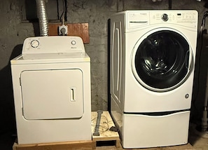 Two stacked washing machines, one on top of the other, with a wooden pallet beneath the bottom one.