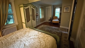 Une chambre à coucher avec un grand lit, une armoire, une chaise et une petite table.