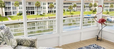 A room with a large window overlooking a water body and a building complex.